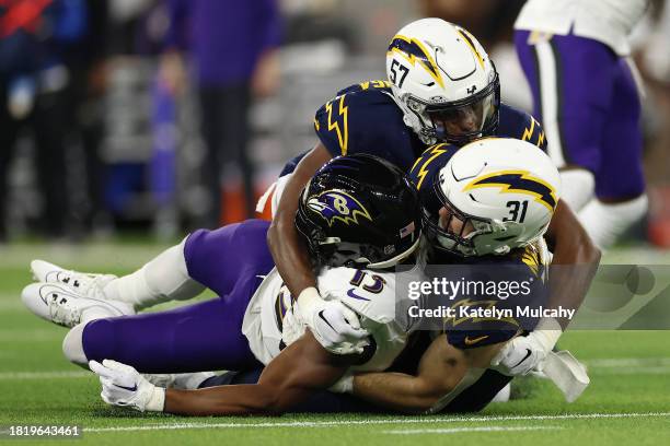 Amen Ogbongbemiga and Nick Niemann of the Los Angeles Chargers tackle Devin Duvernay of the Baltimore Ravens during the second quarter at SoFi...