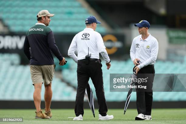 Umpires meet with ground staff before the covers were placed on the pitch during the Sheffield Shield match between New South Wales and Tasmania at...