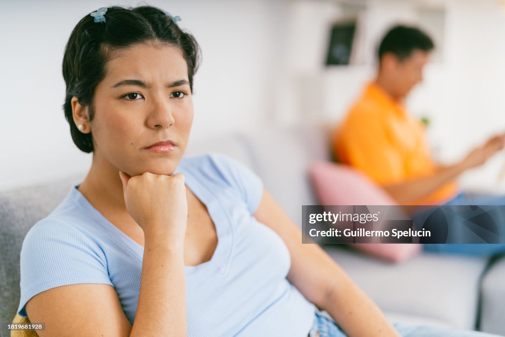 Young woman annoyed with her partner sitting on the couch