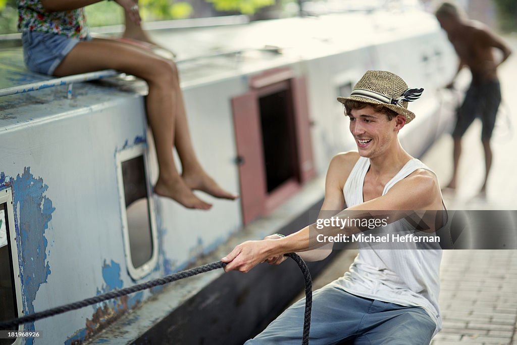 Young man pulling rope on canal boat