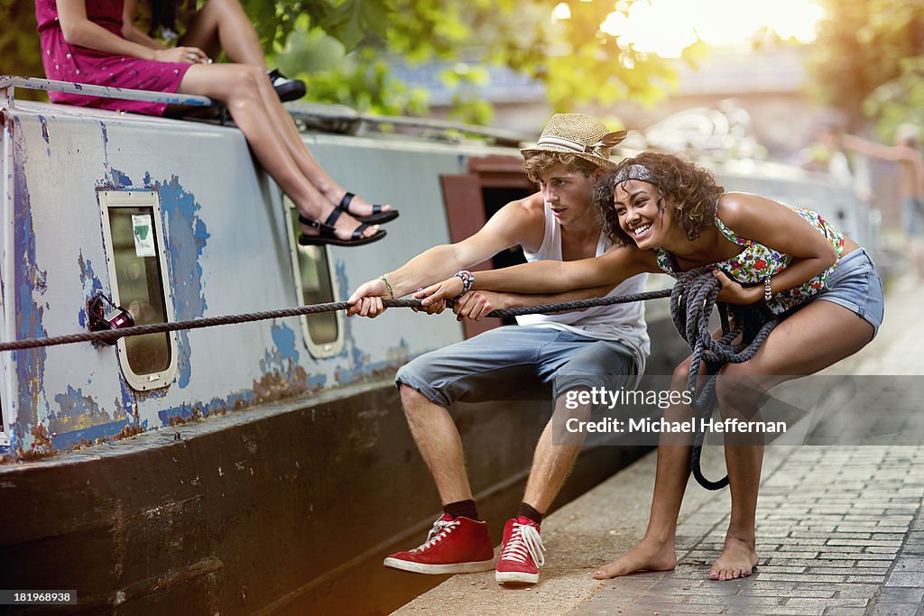 Two young people pulling on canal boat rope