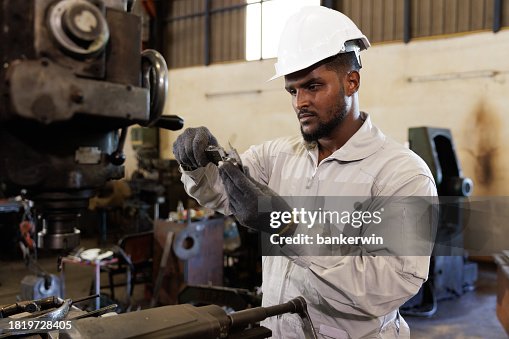 African-American engineer using vernier caliper measuring work piece in factory