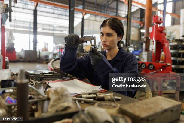 técnica femenina que usa la pieza de trabajo de medición del calibrador vernier en la fábrica - calibrador fotografías e imágenes de stock