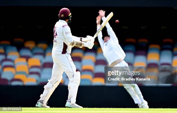 Gurinder Sandhu of Queensland gets the ball past the fielding of Corey Rocchiccioli of Western Australia during day two of the Sheffield Shield match...