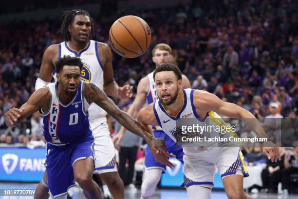 Stephen Curry of the Golden State Warriors competes for a loose ball against Malik Monk of the Sacramento Kings in the fourth quarter during the NBA...