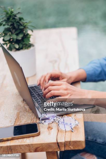 detail shot of woman's hands typing on a laptop in an outdoor setting. - content development stock pictures, royalty-free photos & images
