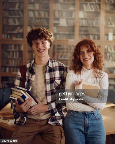 happy high school couple in library. - teen photography stock pictures, royalty-free photos & images