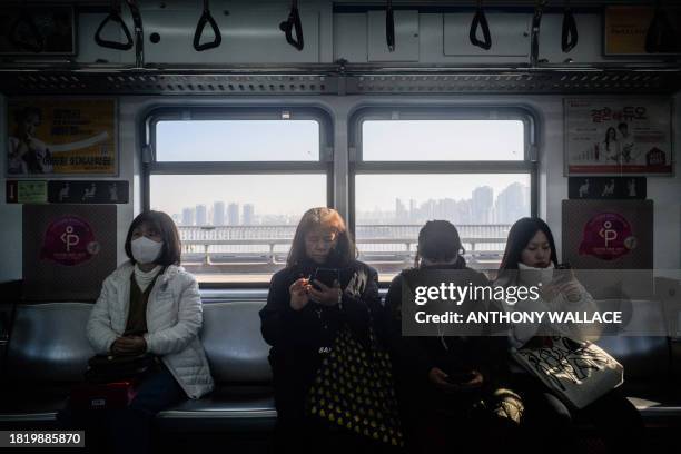 Commuters sit as their metro train crosses a bridge across the Han River in Seoul on December 4, 2023.