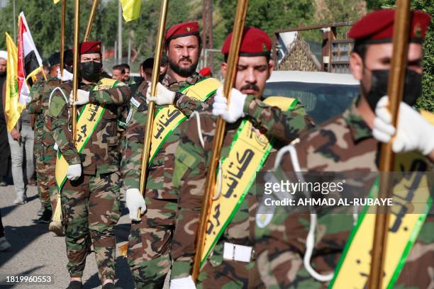 Fighters lift flags of Iraq and paramilitary groups, including al-Nujaba and Kataib Hezbollah, during a funeral in Baghdad for five militants killed...