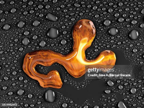 drop of gold colored metallic liquid slides on a wet background with small water bubbles. - bronzo foto e immagini stock