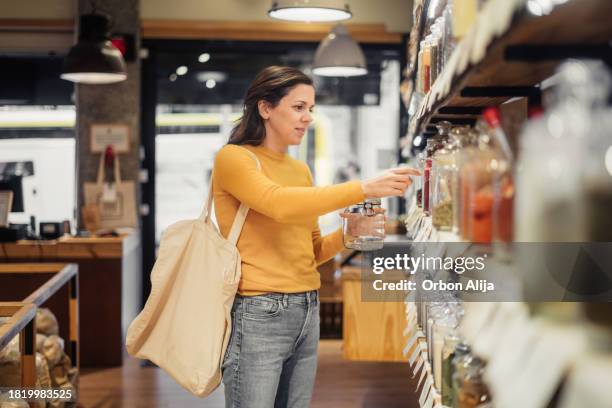mujer comprando en una tienda de residuo cero - tienda de alimentos naturales fotografías e imágenes de stock