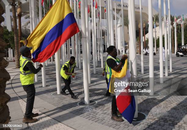Workers hoist flags, including that of Colombia , of nations participating in the UNFCCC COP28 Climate Conference the day before its official opening...