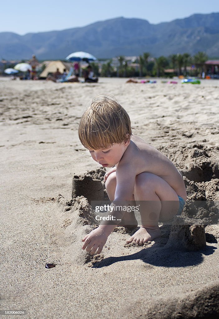 Niño jugando con arena en la playa