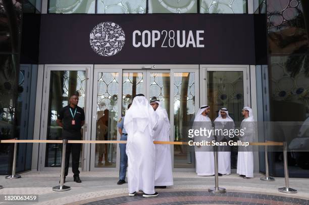 Men wearing thawbs stand outside a venue at the UNFCCC COP28 Climate Conference the day before its official opening on November 29, 2023 in Dubai,...