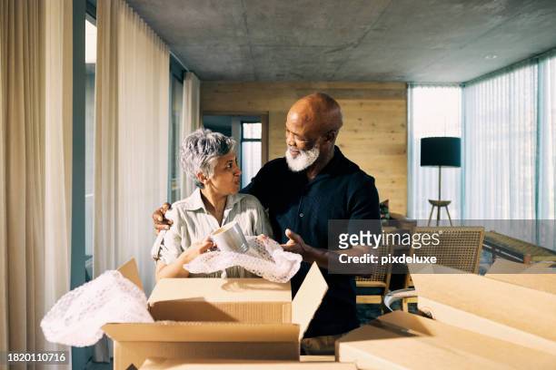 generation x african-american couple unpacking memories and smiling in new home during retirement transition - senior moving house stock pictures, royalty-free photos & images