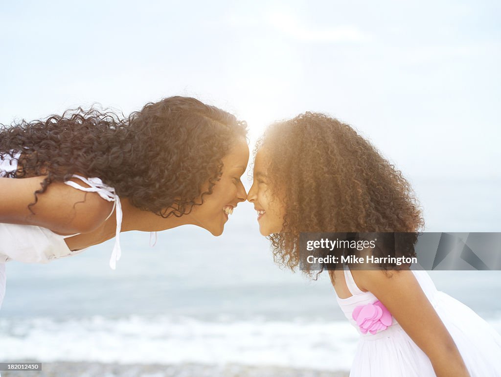 Mother and daughter rubbing noses on beach.