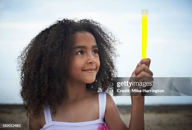 girl standing on beach holding glowstick. - glow stick kids stock pictures, royalty-free photos & images