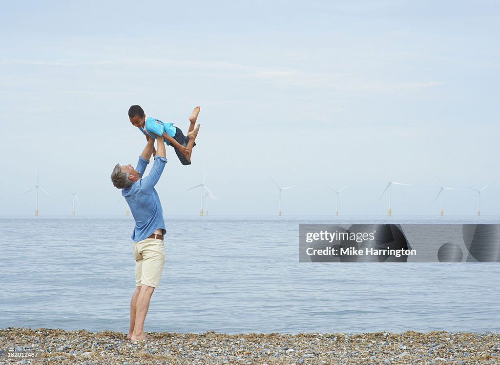 Father holding son up in air on beach.