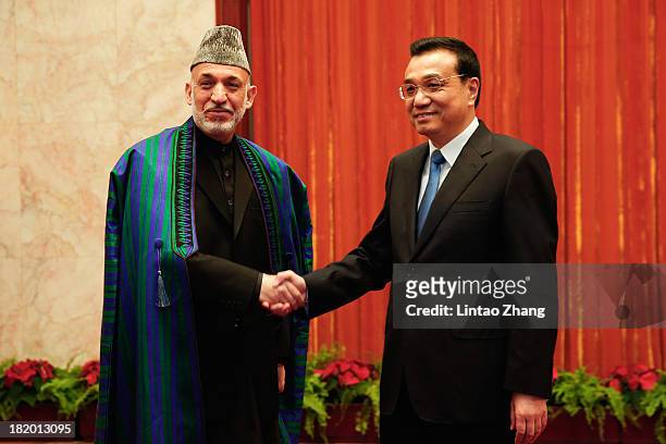 Afghan President Hamid Karzai shakes hands with Chinese Premier Li Keqiang at the Great Hall of the People on September 27, 2013 in Beijing, China....