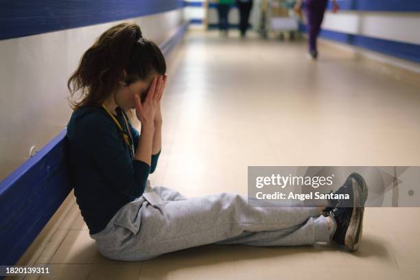 young woman looking worried while sitting on the hospital floor - women stock pictures, royalty-free photos & images