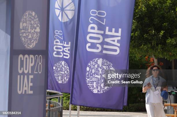Woman walks past banners at the UNFCCC COP28 Climate Conference the day before its official opening on November 29, 2023 in Dubai, United Arab...