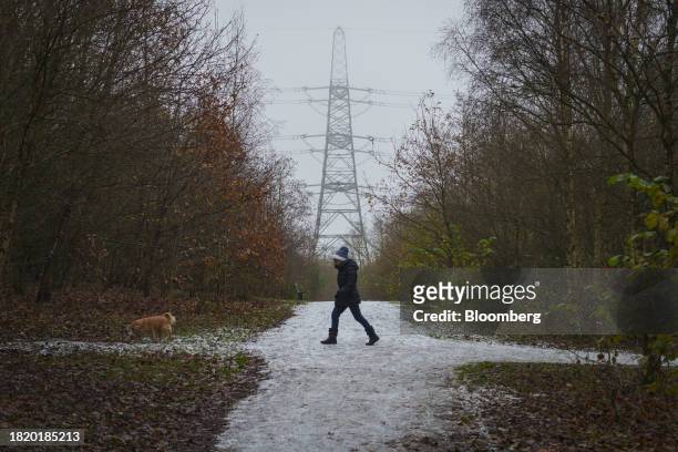 Dog walker passes an electricity pylon on a cold day near the decommissioned Fiddler's Ferry coal fueled power station in Warrington, UK, on Sunday,...
