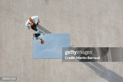 Woman standing above mirror and reflection outdoors Woman standing above mirror and reflection outdoors