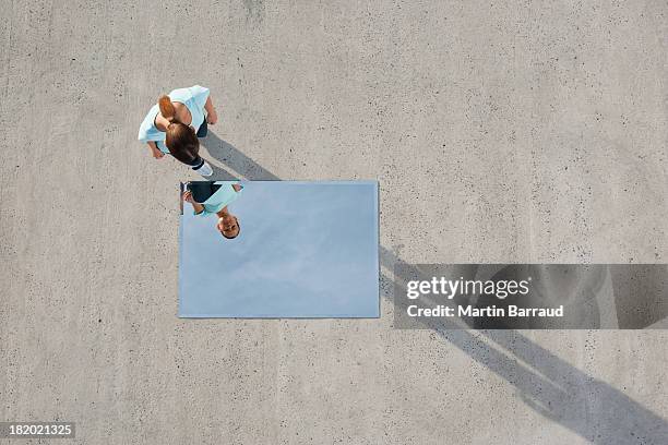 woman standing above mirror and reflection outdoors - weerkaatsing stockfoto's en -beelden