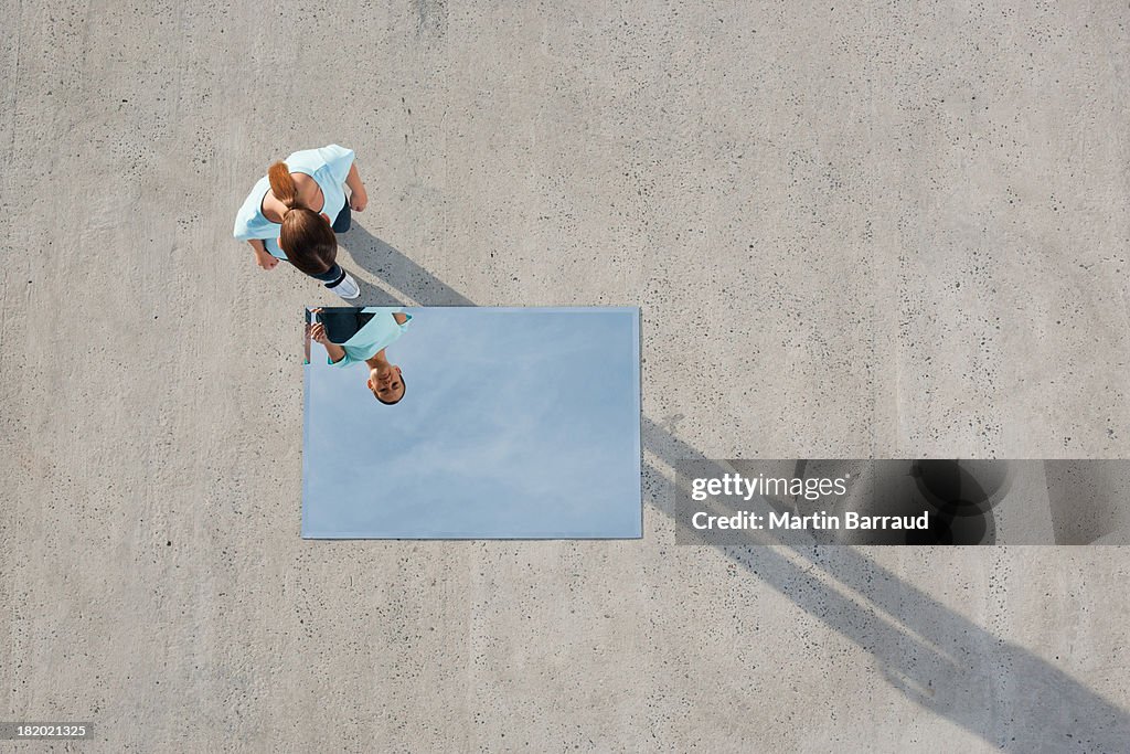 Woman standing above mirror and reflection outdoors