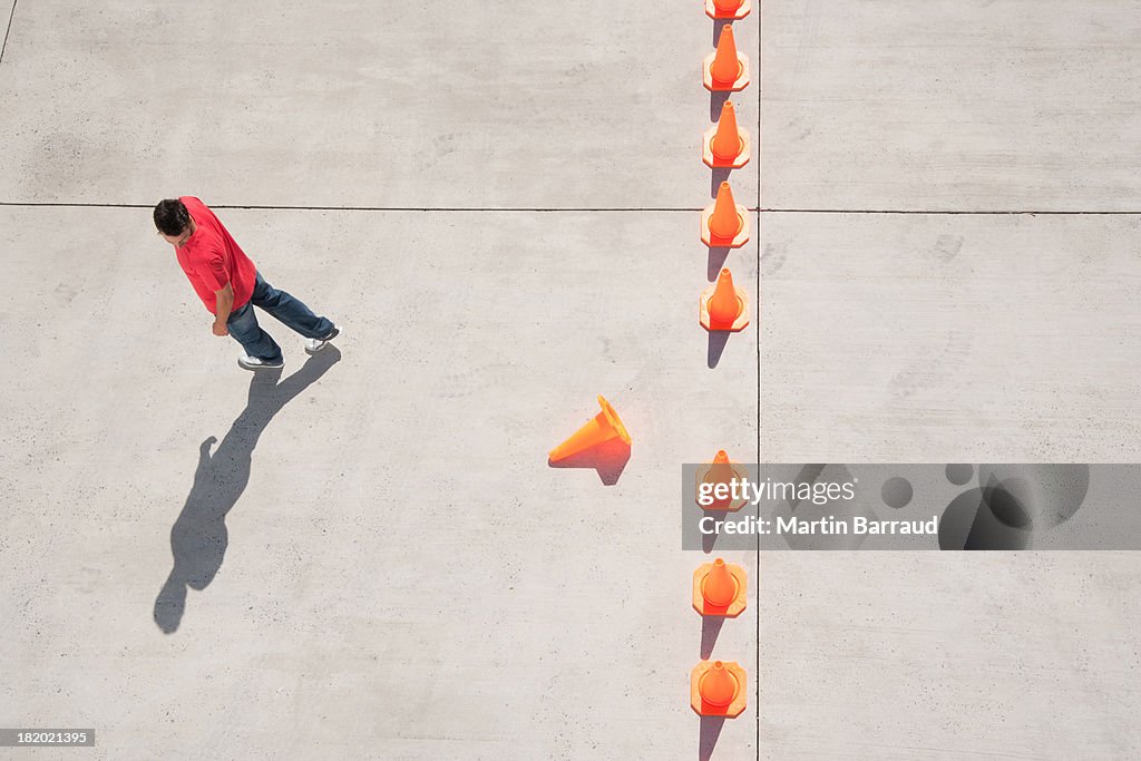 Man looking at row of traffic cones with one misplaced