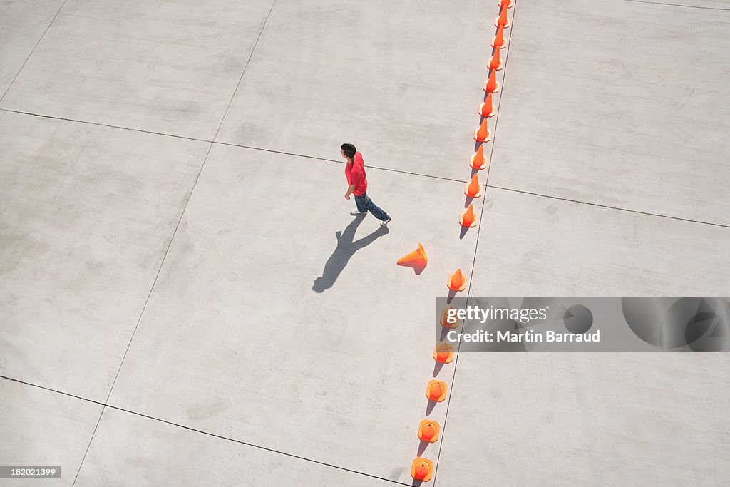 Man walking away from row of traffic cones with one misplaced