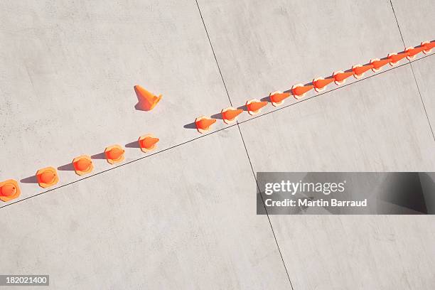 row of traffic cones with one on side - imperfection stockfoto's en -beelden