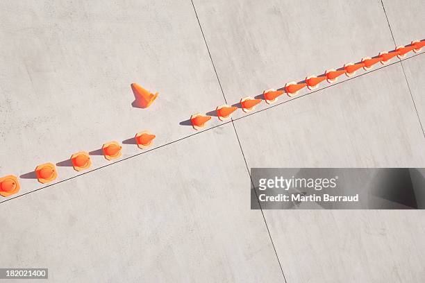 row of traffic cones with one on side - conformity stock pictures, royalty-free photos & images