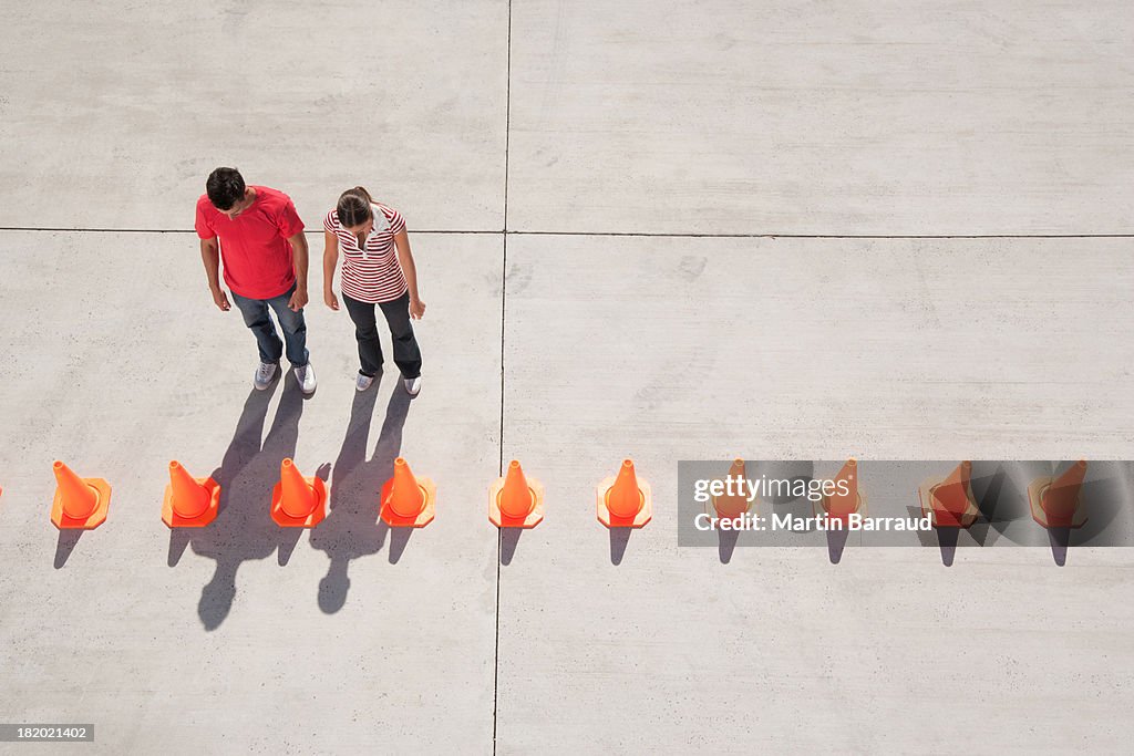 Man and woman looking at row of traffic cones