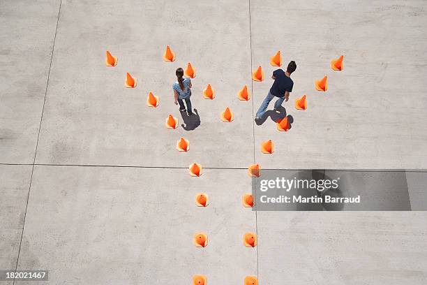 man and woman in traffic cones moving apart - standing apart stock pictures, royalty-free photos & images