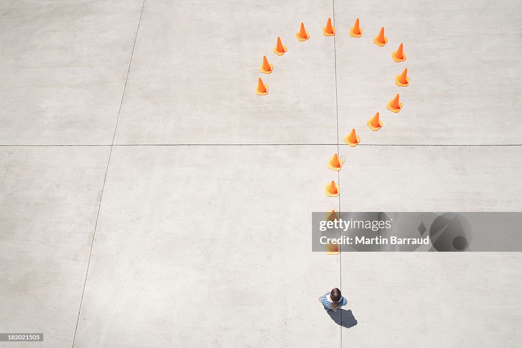 Traffic cones forming question mark with woman at point standing