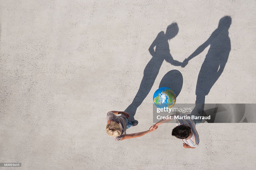 Aerial View of two people shaking hands with shadow and globe outdoors