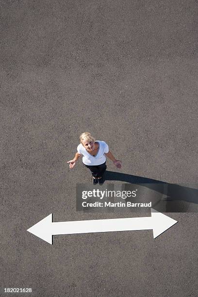 woman standing near arrow on pavement looking up - the next step stock pictures, royalty-free photos & images