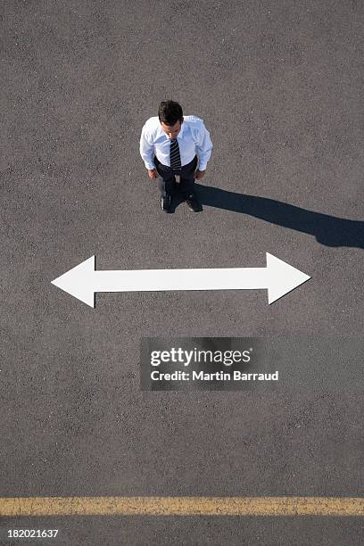 man standing near arrow on pavement  - man with arrow stock pictures, royalty-free photos & images