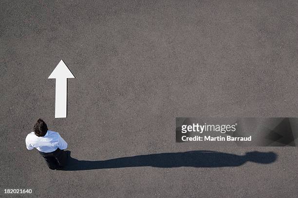 arrow on pavement pointing away from businessman - vision and mission stockfoto's en -beelden