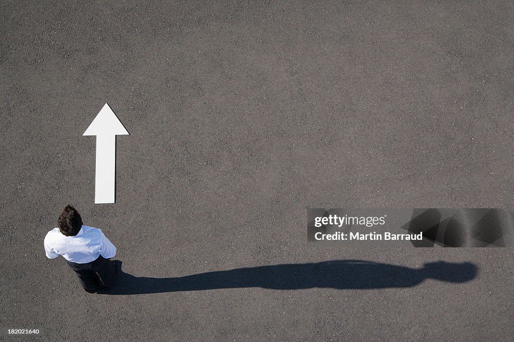 Arrow on pavement pointing away from businessman