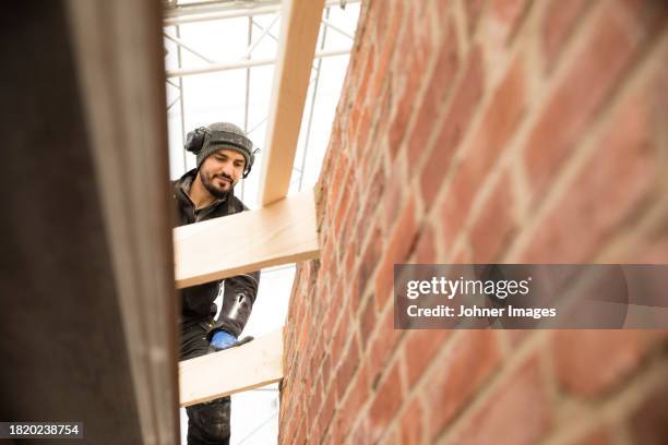 male construction worker at construction site - bouwmateriaal stockfoto's en -beelden
