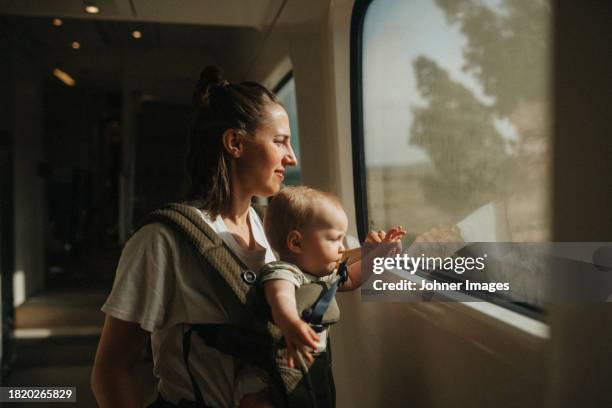 mother with baby looking through train window - zuid europese etniciteit stockfoto's en -beelden