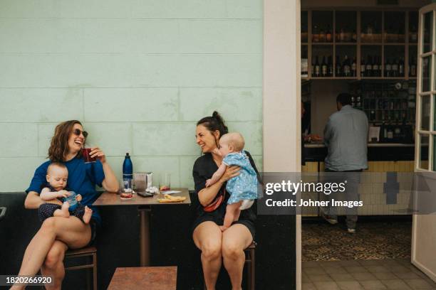 mothers with babies relaxing in sidewalk cafe - terraza de cafetería fotografías e imágenes de stock