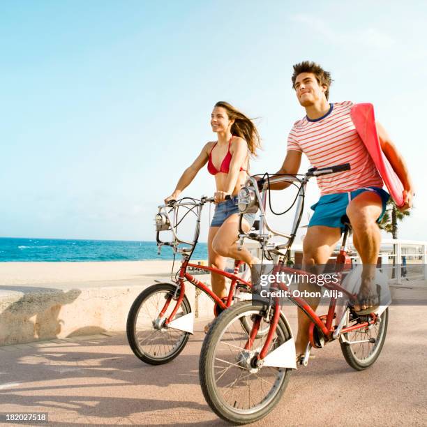 paar reiten fahrrad am strand boardwalk - steg zwei menschen stock-fotos und bilder