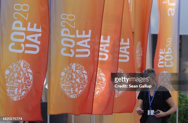 Woman walks past banners at the UNFCCC COP28 Climate Conference the day before its official opening on November 29, 2023 in Dubai, United Arab...