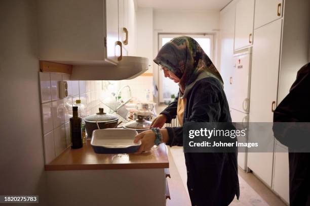 woman in headscarf cooking dinner at home - preparation stock pictures, royalty-free photos & images