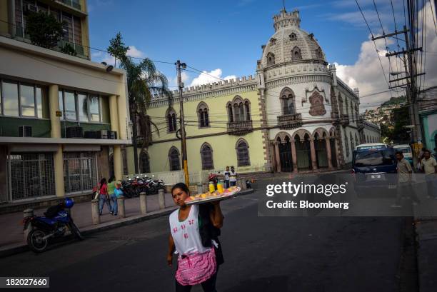 Woman selling fruit walks past the former presidential palace in Tegucigalpa, Honduras, on on Wednesday, Sept. 4, 2013. Economic growth in Honduras...