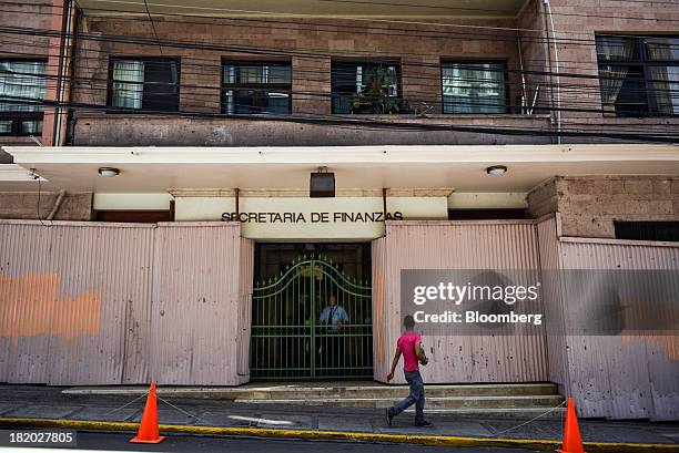 Security guard looks out from behind a metal gate as a pedestrian walks past the Ministry of Finance building in Tegucigalpa, Honduras, on Thursday,...