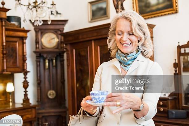 happy mature woman in antique store - antique shop stockfoto's en -beelden